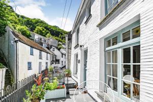 an alley with white houses and a balcony with plants at Teana Cottage in Polperro