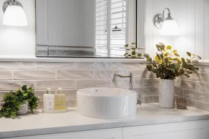 a white bathroom with a sink and flowers on a counter at Foxmount Estate Magnus 2 bedroom in Mount Gambier +4 photos