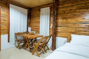 1 dormitorio con mesa, sillas y pared de madera en Panya Garden Resort, en Ban Huai Na