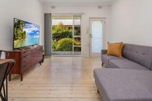 a living room with a couch and a flat screen tv at Stay Here On Pier- 2 Bdrm Sleeps 4 Beach Wifi in Glenelg