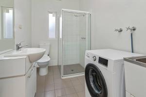 a white bathroom with a washing machine and a sink at Stay Here On Pier- 2 Bdrm Sleeps 4 Beach Wifi in Glenelg
