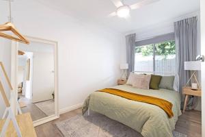 a white bedroom with a bed and a window at Brewers Haus Mainstreet Willunga 2 bdrm sleeps 4 in Willunga