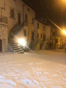 a building with snow on the ground at night at Le dimore nel borgo in Pescocostanzo