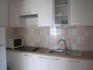 cocina con armarios blancos, fregadero y microondas en Apartments Mirjana, en Sukošan