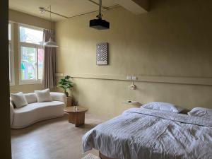 een slaapkamer met een bed en een bank bij Nude in Yilan