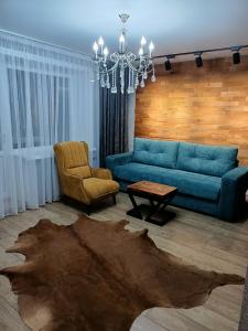 a living room with a blue couch and a chair at Дизайнерская квартира в ста метрах от городского парка in Petropavlovsk