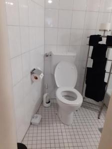 uma casa de banho com WC num quarto com azulejos brancos em Stadt nahes Zimmer im Zentrum von Unna em Unna