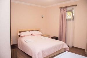 - une chambre avec un lit avec des draps roses et une fenêtre dans l'établissement Spitak tun, à Ijevan