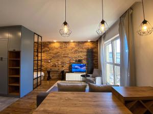 een woonkamer met een tafel en een woonkamer met een bakstenen muur bij BP Apartment in Toruń