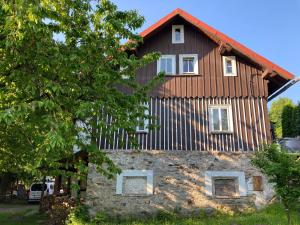 Cette grande maison en bois est située au-dessus d'un mur en pierre. dans l'établissement Vila Adélka - útulná chalupa v Krkonoších, à Horní Maršov