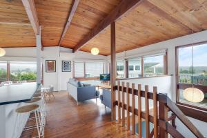 a living room with wood ceilings and windows at 17 Dulling Street Beach House in Dalmeny