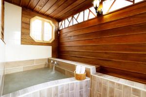 Gorgeous Hot Spring Resort في تايبيه: حمام مع حوض استحمام ساخن مع جدران خشبية