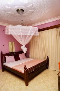 1 dormitorio con 1 cama con paredes de color rosa y techo en Prax suits, en Kampala