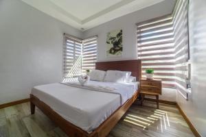 a bedroom with a bed and a table and windows at Bella Homes 6BR near Rotunda, WiFi, Parking in Tagaytay