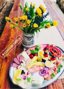 a plate of food on a table with a vase of flowers at Cabana Din Poienita in Poiana Brasov
