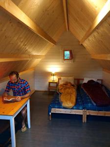 Ein Mann, der an einem Tisch in einem Zimmer mit einem Bett sitzt. in der Unterkunft Slaaphutje BuitenWedde Westerwolde in Wedde