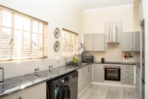 a large kitchen with white cabinets and a dishwasher at Bottle Brush Place WITH SOLAR in Roodepoort