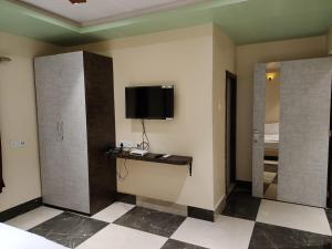um quarto com uma televisão numa parede com um piso de xadrez em STAYMAKER Addyama - Only Indian Citizens Allowed em Calcutá