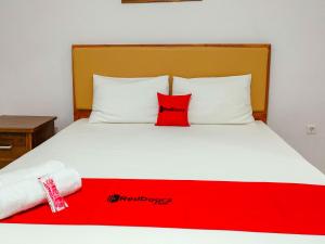 Una cama con una almohada roja encima. en RedDoorz at Omah Candi Sari near Airport YIA en Yogyakarta