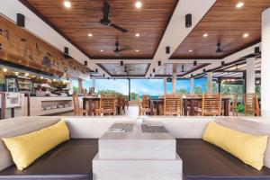 a restaurant with wooden ceilings and tables and chairs at Holiday Ao Nang Beach Resort, Krabi - SHA Extra Plus in Ao Nang Beach