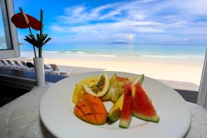 a plate of fruit on a table near the beach at Coral Strand Smart Choice in Beau Vallon