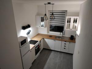 La cuisine est équipée de placards blancs et d'un four avec plaques de cuisson. dans l'établissement Apartmán One To One, à Štúrovo