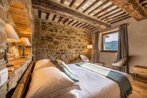 a bedroom with a bed and a stone wall at Stelle di Monte in Montepulciano