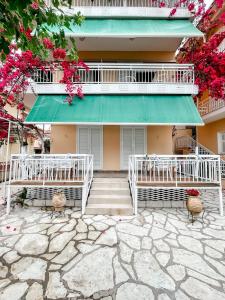a building with a green awning and chairs and flowers at Avli Studios in Nydri