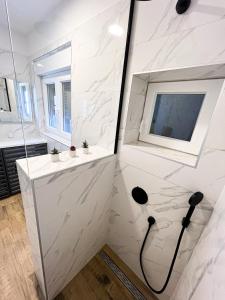a white bathroom with a shower and a sink at SanOne-Studio apartment in Jesenice