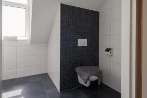 łazienka z toaletą w czarnej ścianie w obiekcie Woning "Villa Zoutelande" w mieście Zoutelande