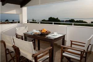 a table with chairs and a bowl of fruit on a balcony at Ionio Holidays Katerina Apartments in Vasilikos