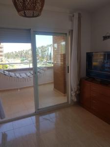 ein Wohnzimmer mit einer Glasschiebetür und einem TV in der Unterkunft Marina dor Frontal 1ª línea in Oropesa del Mar