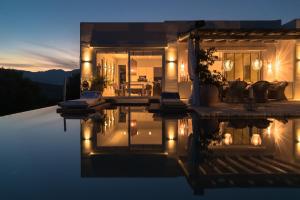 a house with a reflection in the water at night at Shangri-La in Meganisi +22 photos