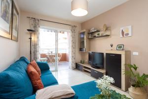 sala de estar con sofá azul y TV en Vivienda vacacional en Caletillas Piscina yWIFI, en Candelaria