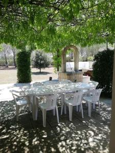 una mesa blanca y sillas bajo un árbol en Villa del glicine, en Muro Leccese