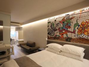 a hotel room with a bed and a wall with a mural at Link Hotel & Hub By Dan Hotels in Tel Aviv