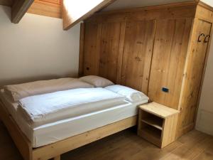 a bed in a room with a wooden wall at B&B el Benel in Ossana