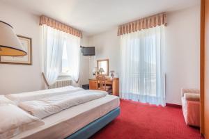 a bedroom with a bed and a large window at Hotel Lucia in Levico Terme