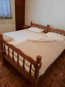 uma grande cama de madeira com duas almofadas em Privatan smeštaj Igalo em Igalo