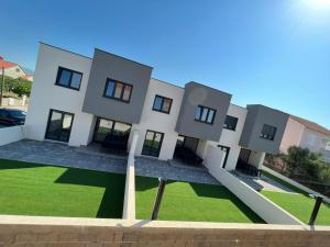 a white house with a green lawn in front of it at Residence Doli in Vrsi