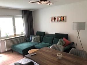a living room with a green couch and a table at Four Seasons Bodensee in Eriskirch