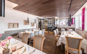 una sala da pranzo con tavoli e sedie bianchi di Paradies Pure Mountain Resort a Solda