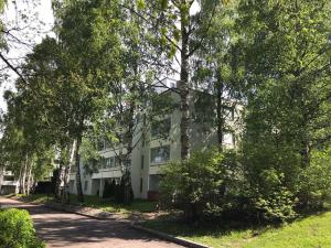 Un edificio blanco con árboles delante. en Spacious 1bdrm apartment near metro. Free parking, en Vantaa