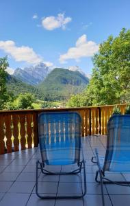 twee stoelen op een veranda met bergen op de achtergrond bij Apartma Vovk in Mojstrana