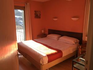 a bedroom with a bed with orange walls and a window at Hotel Roc de St Miquel & Apartment in Soldeu