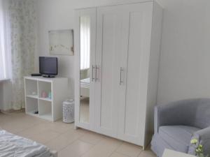 1 dormitorio con armario blanco y TV. en Ferienwohnung Finn im Haus Maarten en Cuxhaven