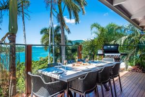 a dining table on a deck with a view of the ocean at Coral Sea Pearl in Shute Harbour