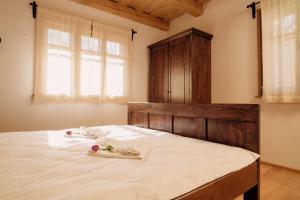 a bedroom with a large white bed with a wooden headboard at Körtövés Guest Village in Vîrghiş