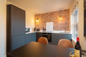 una cucina con tavolo, sedie e muro di mattoni di Capri Stays - Apartment Two - Two Bed Apartment a Blackpool