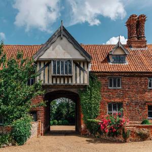 stary ceglany dom z łukiem przed nim w obiekcie Lavish Tudor Estate & Gardens - Sleeps 25 w mieście Hales